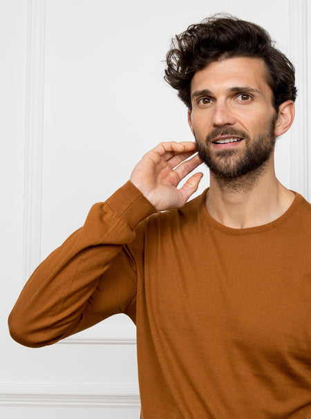 Man wearing ginger/burnt orange crewneck sweater knit in 100% luxury and premium merino wool.